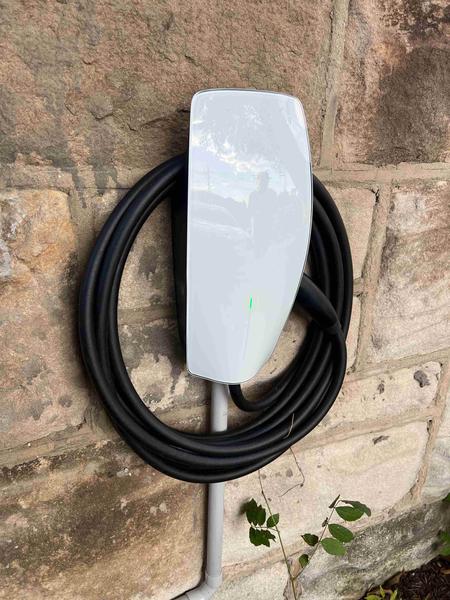 An EV charger installed on a stone garage wall